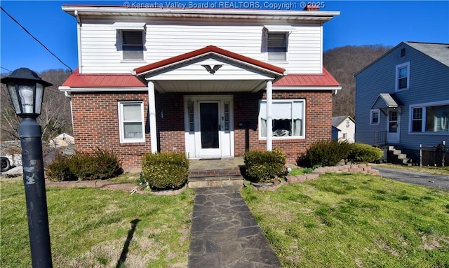 american foursquare style home featuring metal roof, brick siding, and a front yard