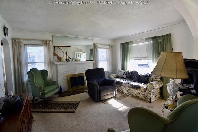 living area featuring a wealth of natural light, a brick fireplace, carpet flooring, and a textured ceiling