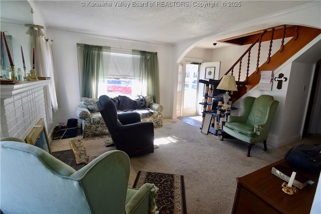 carpeted living room featuring arched walkways, stairs, crown molding, a textured ceiling, and a fireplace
