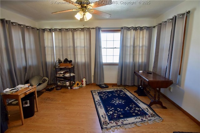 interior space with a ceiling fan, baseboards, and light wood finished floors