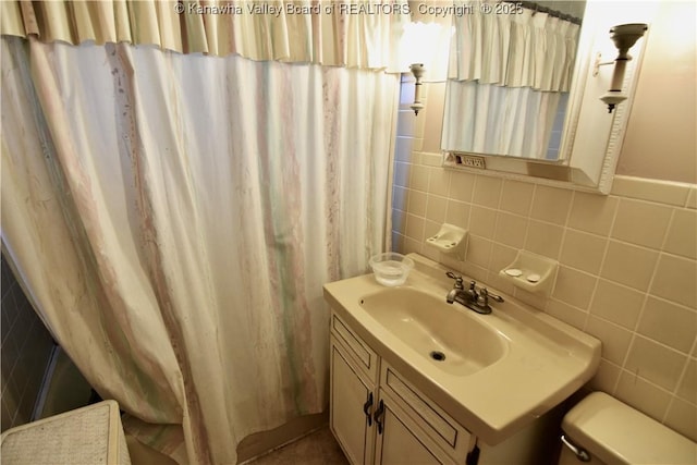 bathroom with toilet, tile walls, and vanity