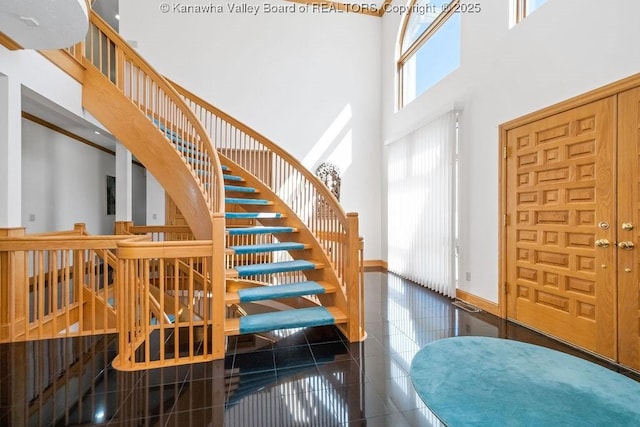 foyer entrance featuring a towering ceiling, baseboards, and dark tile patterned flooring