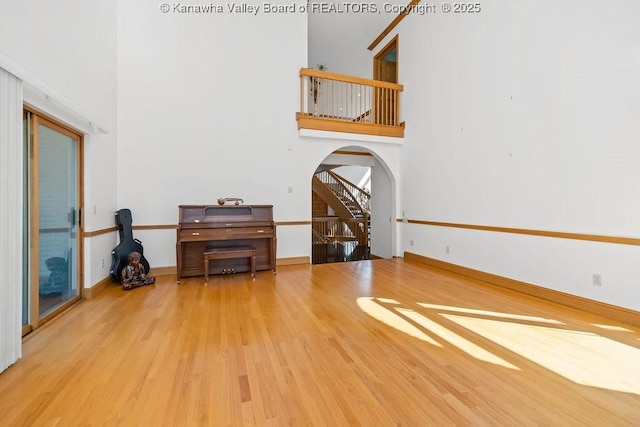 living area with baseboards, a high ceiling, arched walkways, and wood finished floors