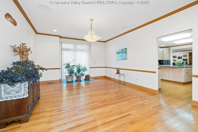 interior space with light wood-style floors, a notable chandelier, baseboards, and crown molding