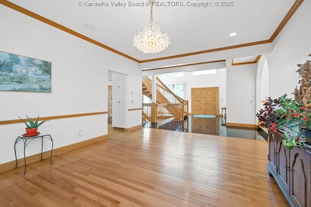 interior space featuring crown molding, an inviting chandelier, baseboards, and light wood-style floors