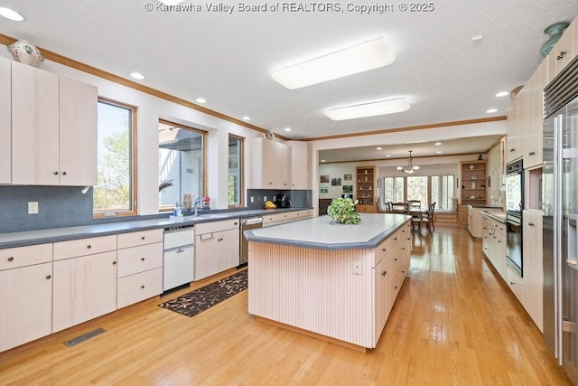 kitchen featuring crown molding, white cabinets, stainless steel dishwasher, a center island, and pendant lighting