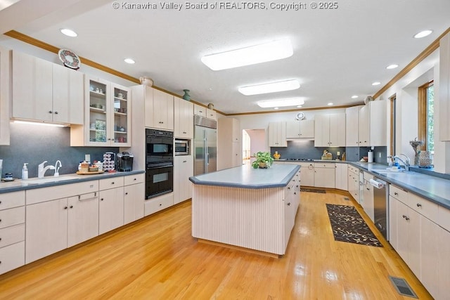 kitchen with built in appliances, a kitchen island, and white cabinets