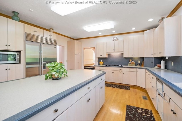 kitchen featuring light countertops, appliances with stainless steel finishes, light wood-type flooring, and decorative backsplash