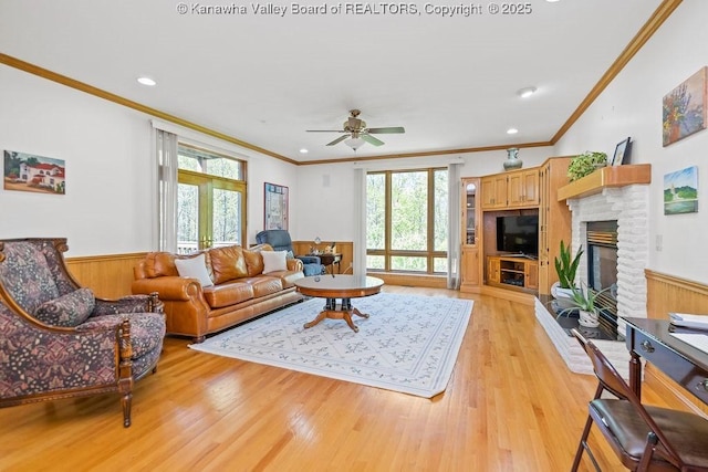 living room with light wood-type flooring, a fireplace, french doors, and wainscoting