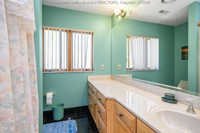 full bath featuring vanity, visible vents, a textured ceiling, and tile patterned floors