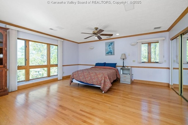 bedroom with ornamental molding, light wood-type flooring, visible vents, and baseboards