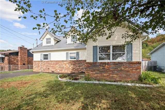 view of front of property with brick siding, a front yard, metal roof, fence, and cooling unit