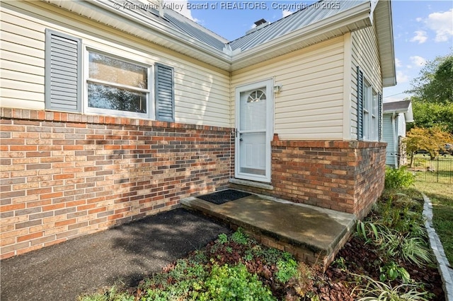 entrance to property featuring brick siding and metal roof