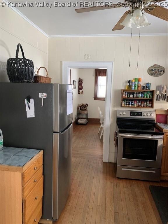 kitchen with ornamental molding, appliances with stainless steel finishes, brown cabinetry, and wood finished floors