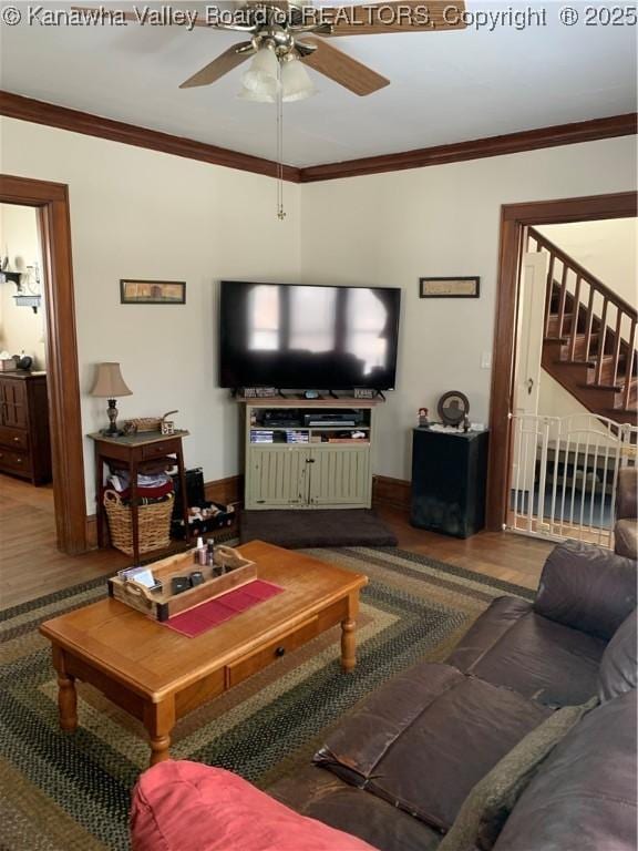 living area with a ceiling fan, stairway, crown molding, and wood finished floors