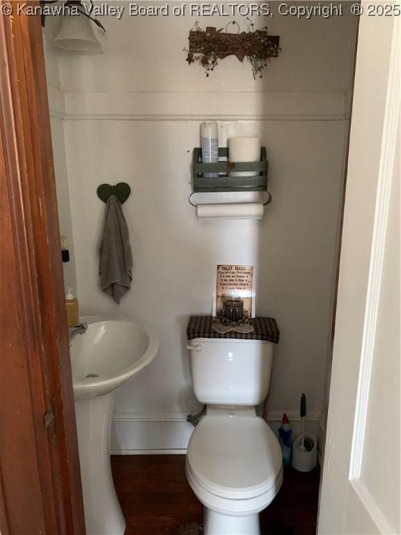 bathroom with baseboards, toilet, and wood finished floors