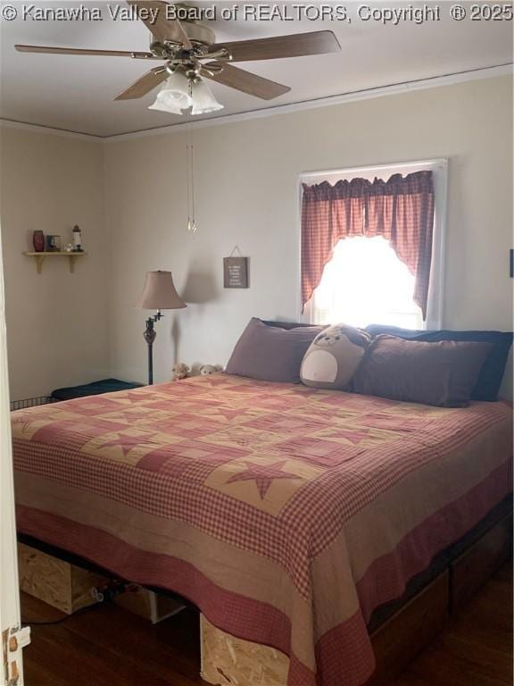 bedroom featuring a ceiling fan, crown molding, and wood finished floors