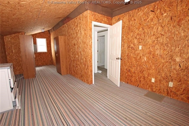 bonus room with lofted ceiling and dark carpet