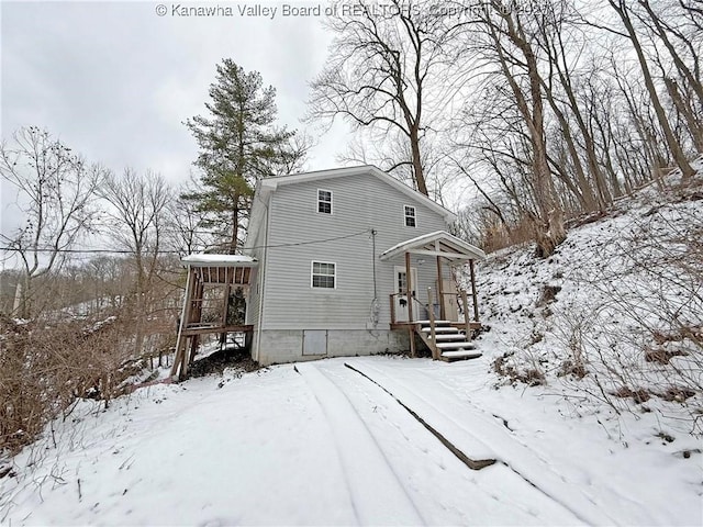 snow covered back of property featuring a garage