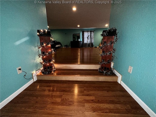 room details featuring a textured wall, baseboards, and wood finished floors