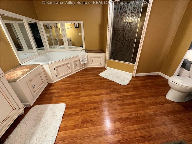 full bath featuring a garden tub, toilet, and wood finished floors