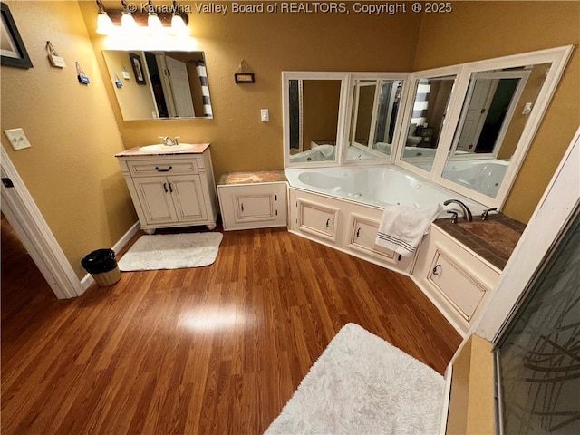 full bathroom featuring baseboards, vanity, a whirlpool tub, and wood finished floors