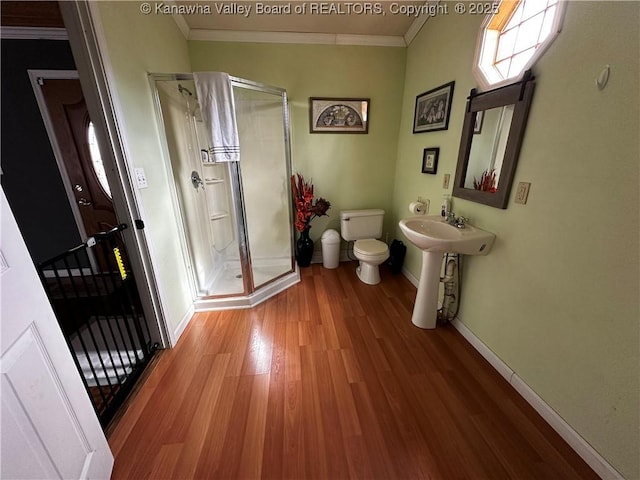 full bath featuring ornamental molding, a shower stall, and wood finished floors