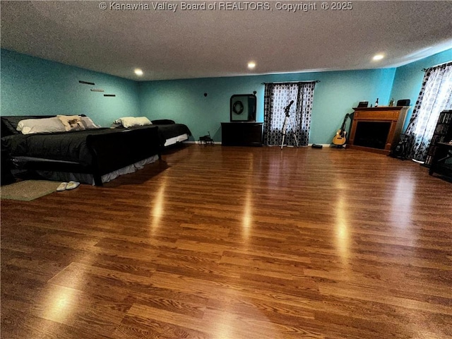 living room featuring a textured ceiling, dark wood-style flooring, a fireplace, and recessed lighting