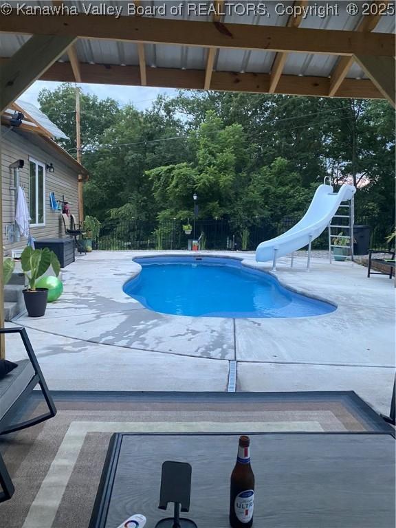 view of pool with a fenced in pool, a water slide, a patio area, and fence