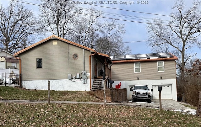 rear view of house featuring a garage and solar panels