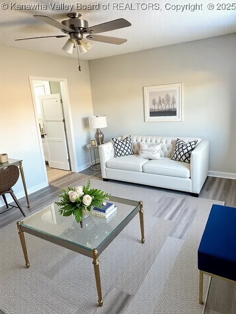 living room featuring baseboards, a textured ceiling, wood finished floors, and a ceiling fan