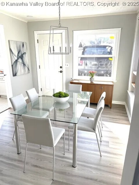 dining space featuring light wood-type flooring, baseboards, and ornamental molding