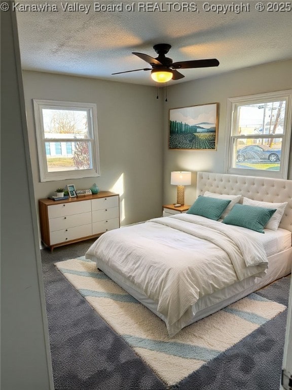 carpeted bedroom featuring multiple windows, a textured ceiling, and ceiling fan