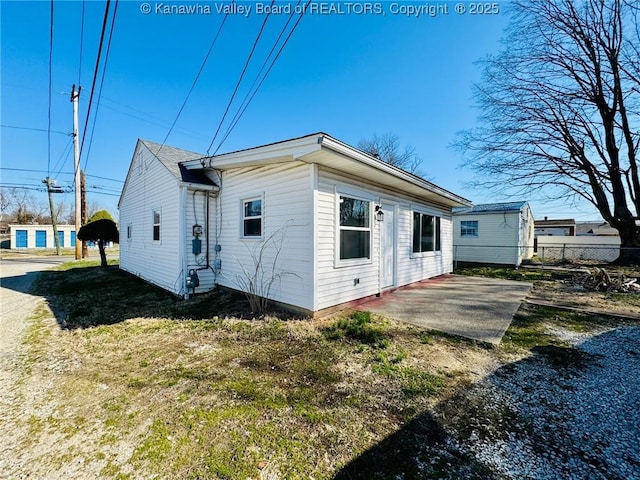 view of property exterior with a yard, a patio, and fence