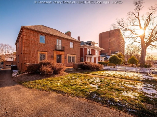 rear view of property with a chimney, fence, and brick siding