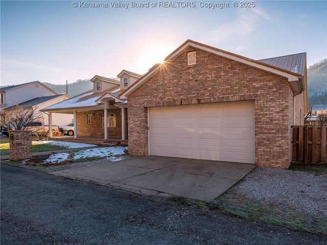 view of front facade with a garage, brick siding, driveway, and fence