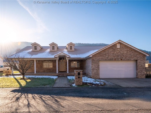 view of front of home with metal roof, concrete driveway, brick siding, and a garage