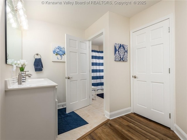 bathroom featuring curtained shower, wood finished floors, vanity, and baseboards