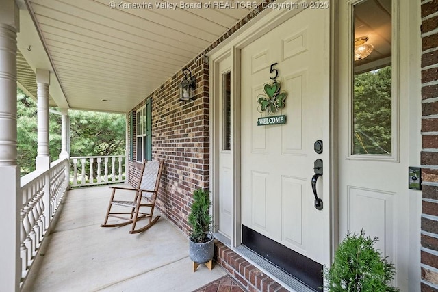 property entrance featuring covered porch and brick siding