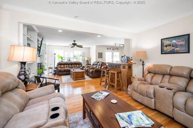 living room with light wood-type flooring, a ceiling fan, crown molding, and recessed lighting