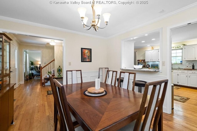 dining space with a notable chandelier, crown molding, and light wood-style flooring