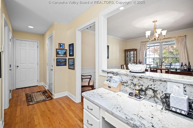 kitchen featuring a chandelier, light wood-type flooring, white cabinets, and crown molding