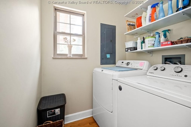 washroom featuring laundry area, electric panel, baseboards, wood finished floors, and washing machine and clothes dryer