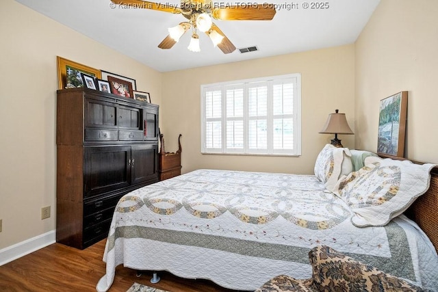 bedroom with ceiling fan, wood finished floors, visible vents, and baseboards