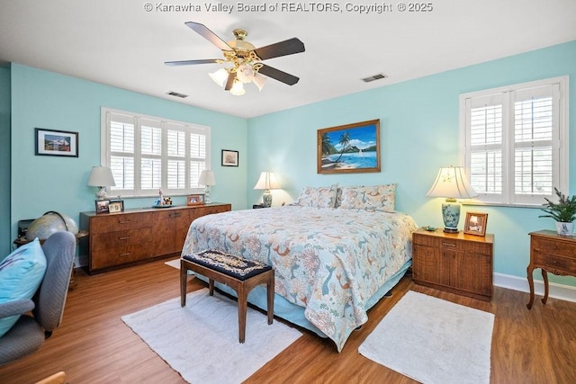 bedroom featuring multiple windows, visible vents, and wood finished floors