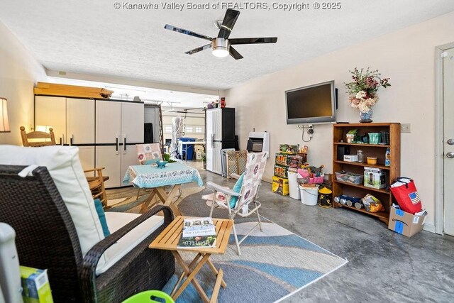 playroom with a textured ceiling, ceiling fan, and concrete floors