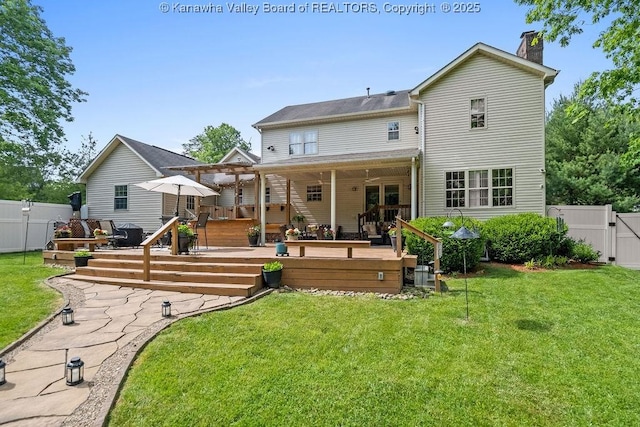 rear view of house featuring a gate, a yard, a deck, and fence