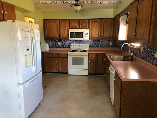 kitchen featuring white appliances, brown cabinets, a sink, and decorative backsplash