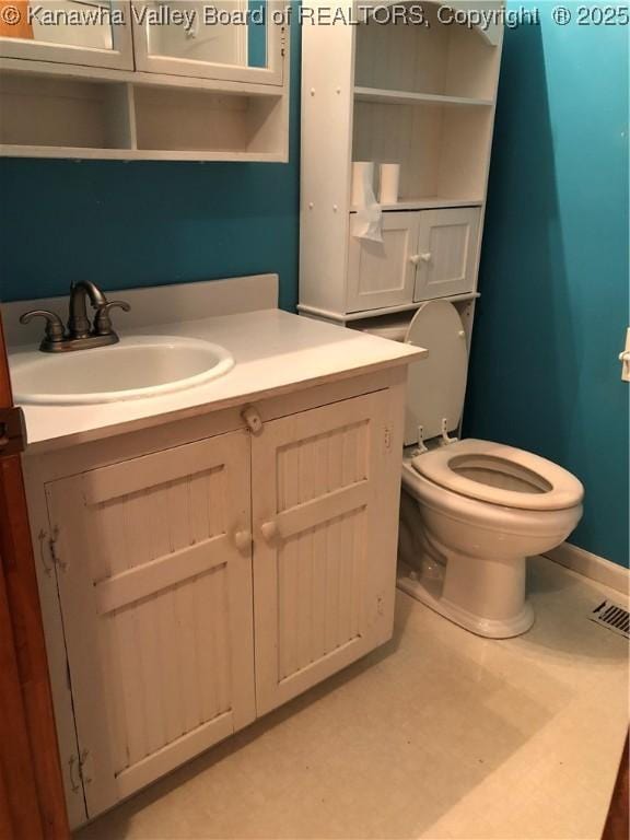 bathroom featuring baseboards, vanity, and toilet