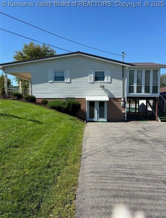 view of front of house with a sunroom, brick siding, and a front lawn